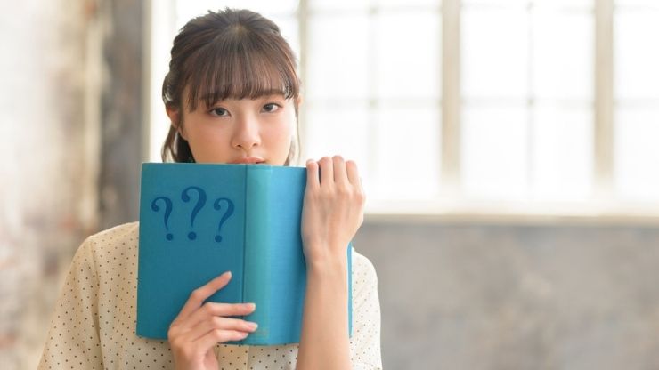 ?マークの本を持つ女性